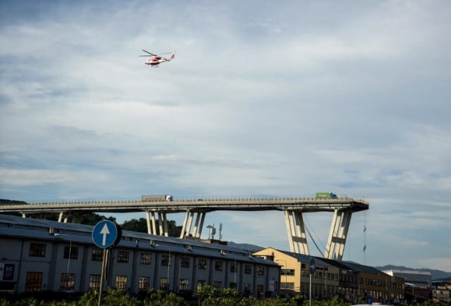 An Italian fire and rescue service helicopter flies over the site after a section of the Morandi motorway bridge collapsed earlier in Genoa on August 14, 2018. Photo: Photo: Federico Scoppa / AFP